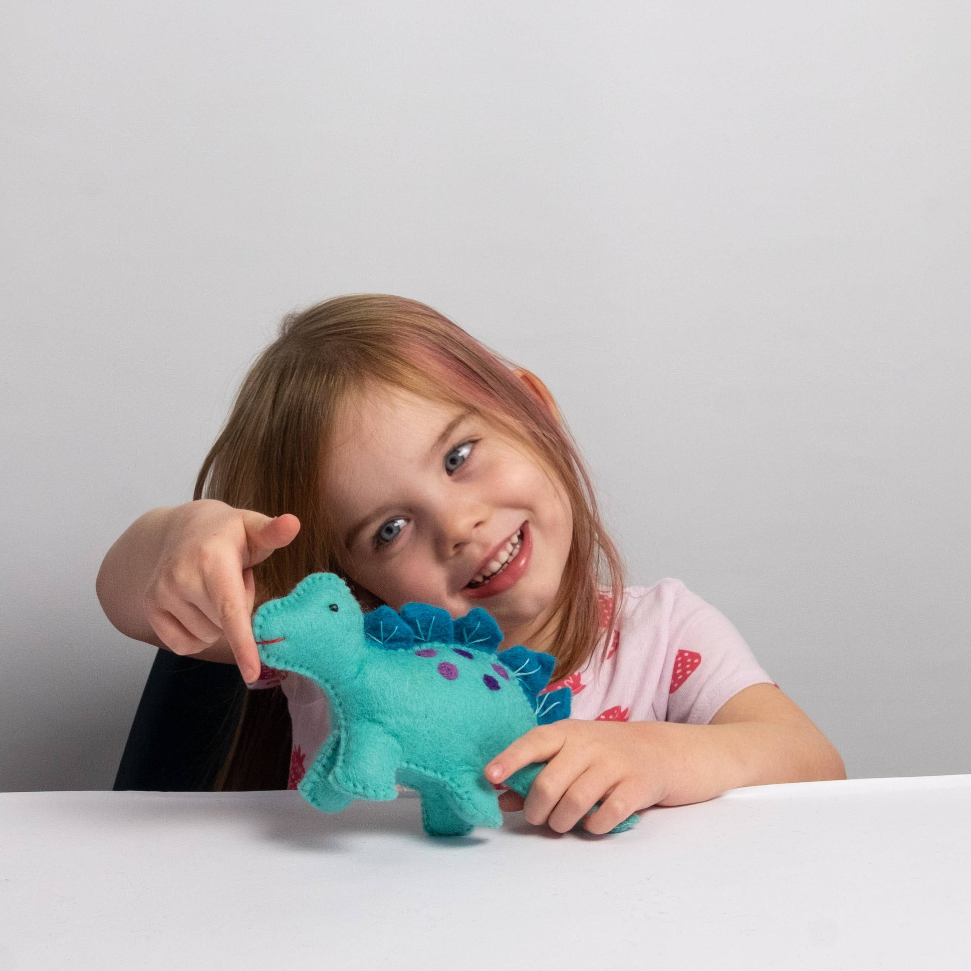 child playing with felt blue baby dinosaur