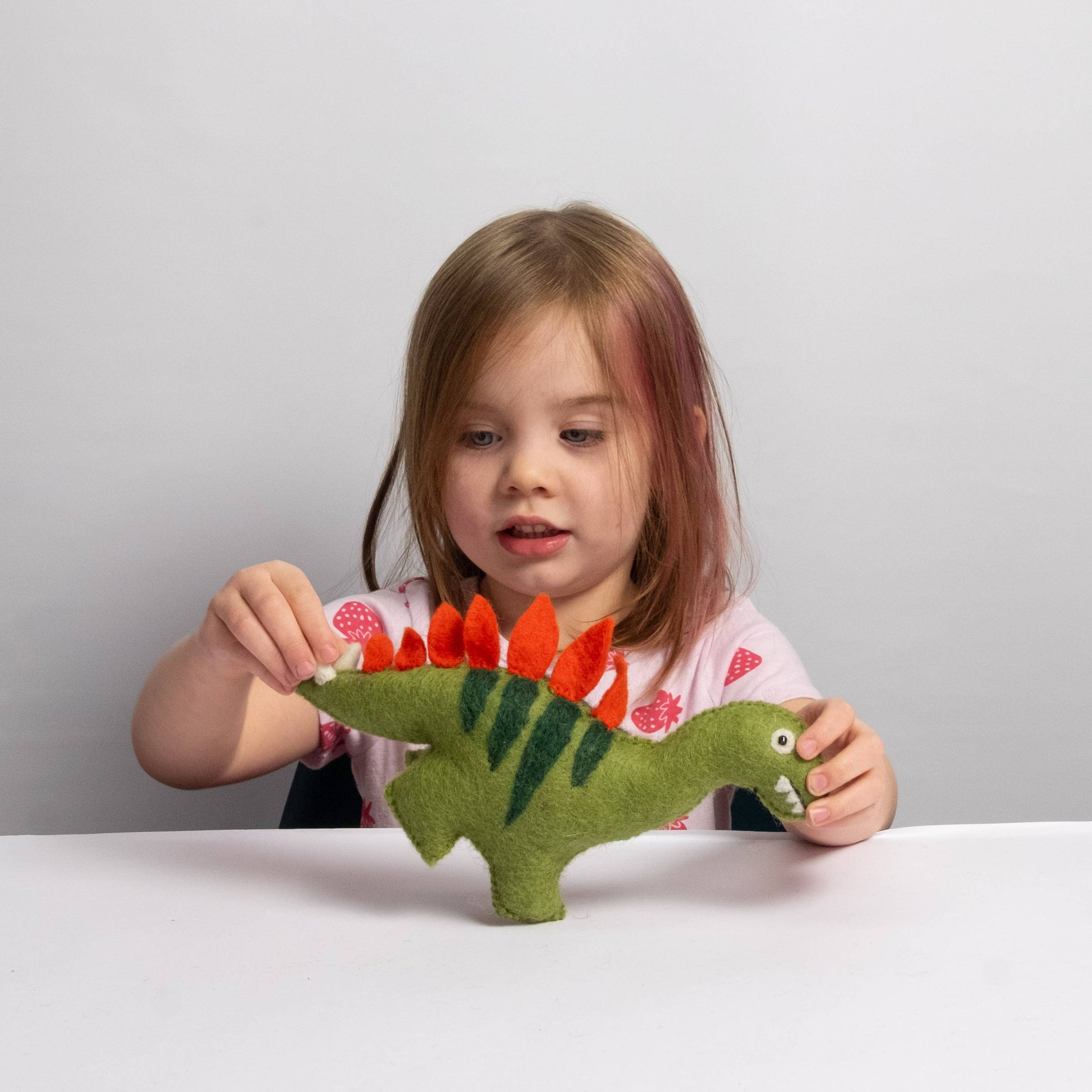 child playing with a wool felt stegosaurus