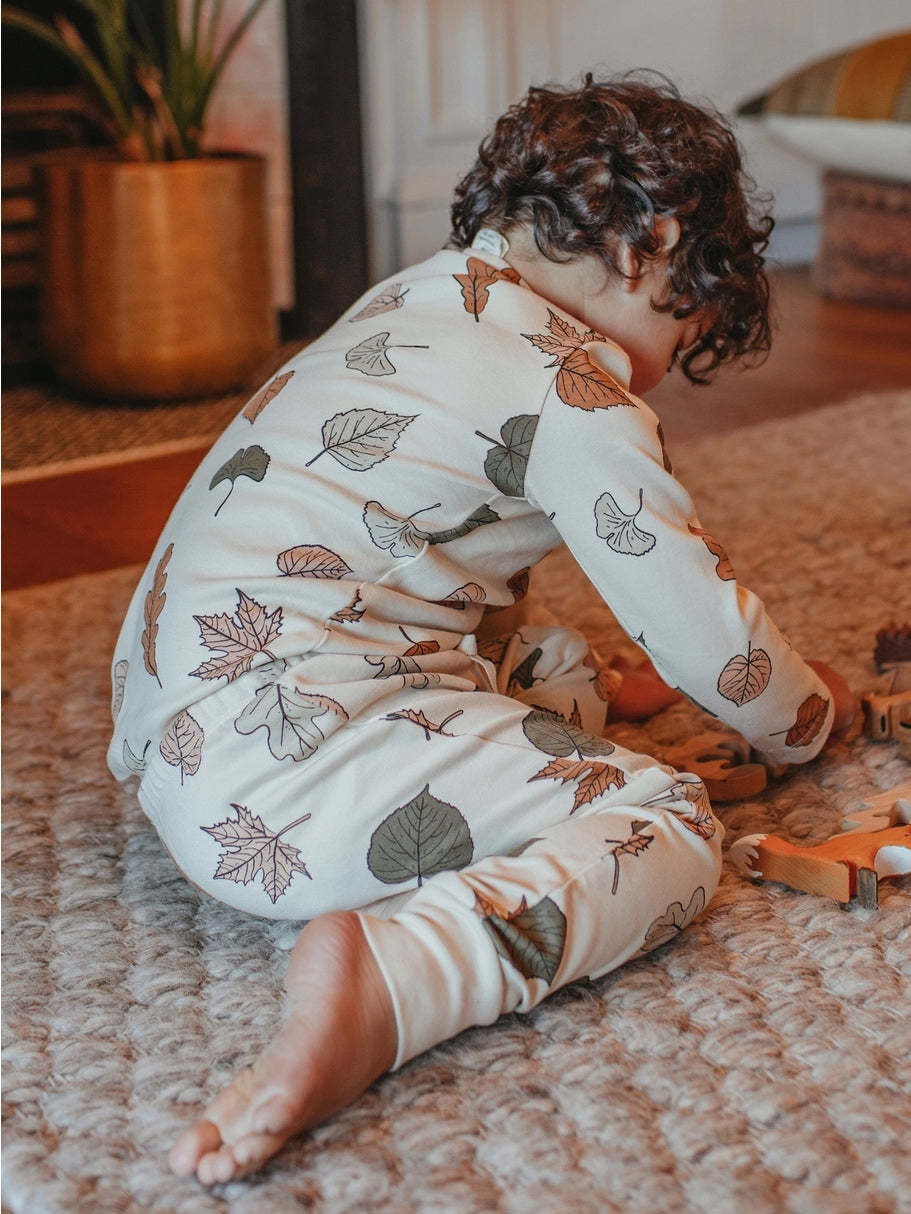 child playing on the floor wearing long sleeve autumn leaf set