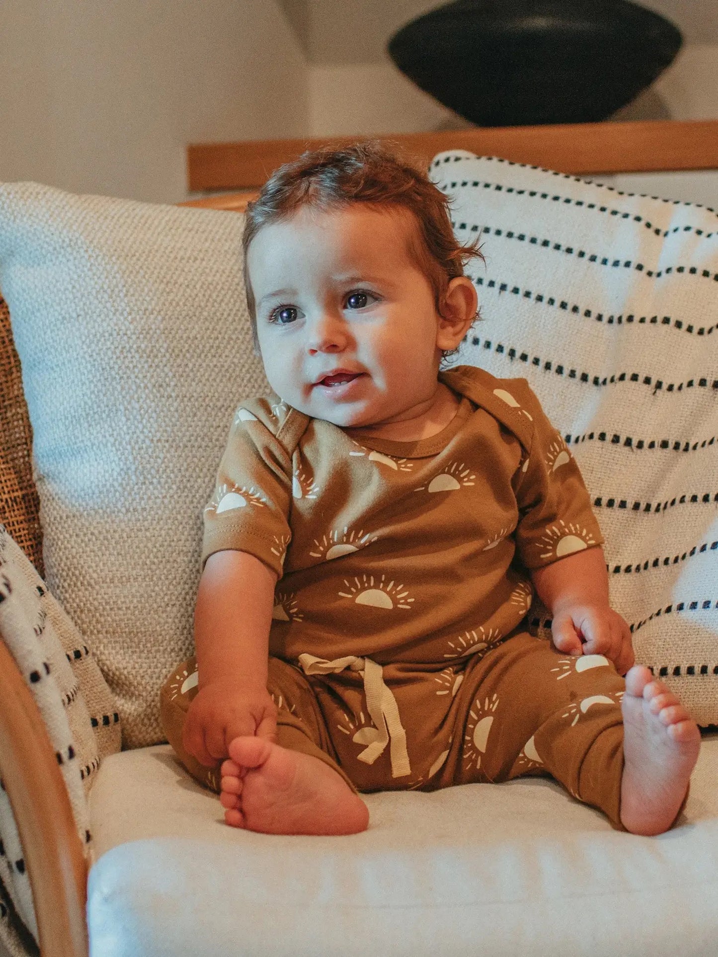 baby sitting on a couch wearing a sun short sleeve onesie and drawstring pants set by Ziwi Baby