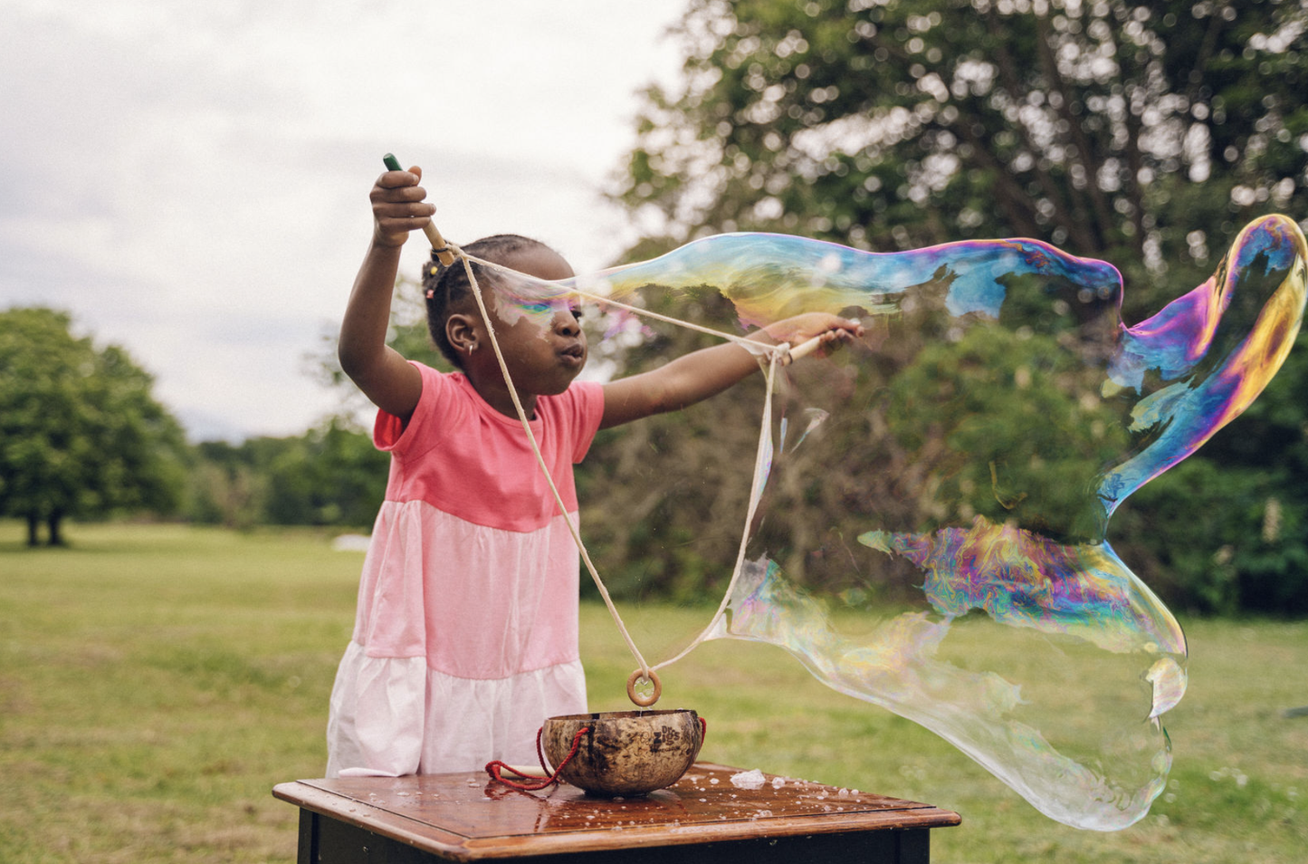 Child blowing a giant bubble with the coconut bucket kit