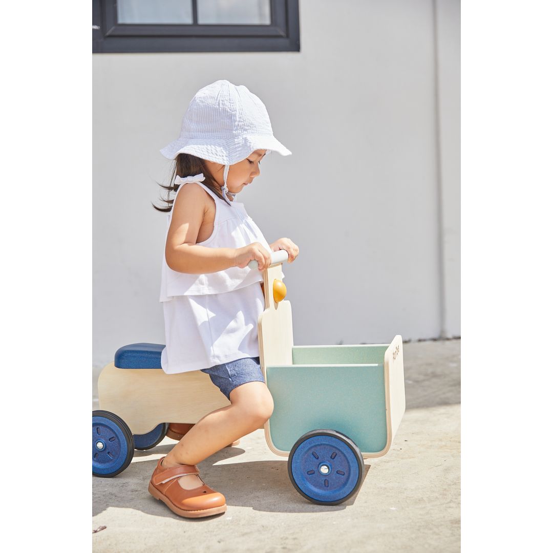 Child playing with a Delivery Bike in Orchard  by plan toys
