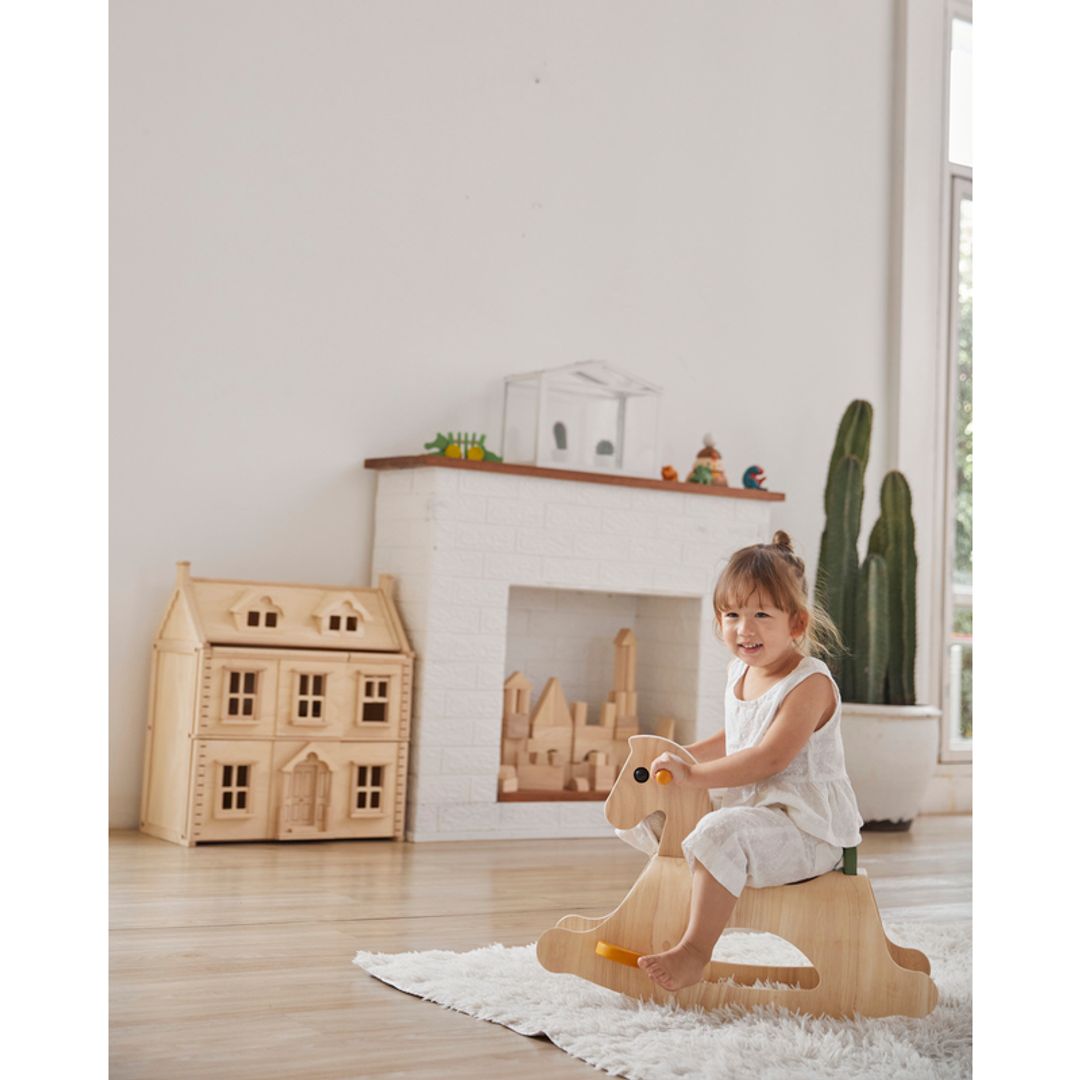 Child riding the PlanToys Palomino Modern Rustic in a play room