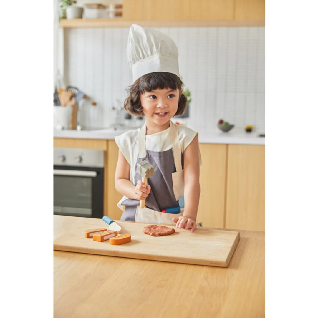 Child wearing and playing with chef set by PlanToys