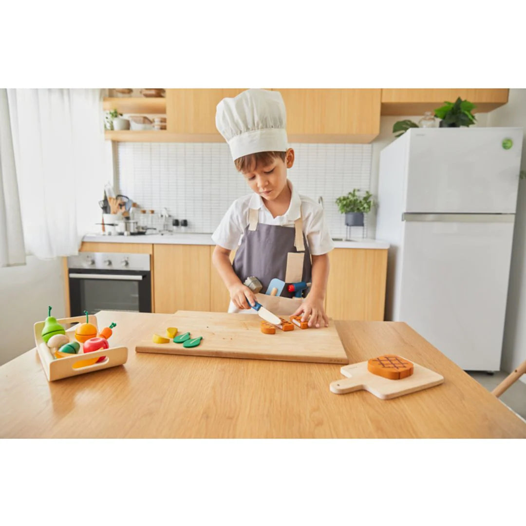 Child wearing and playing with chef set by PlanToys