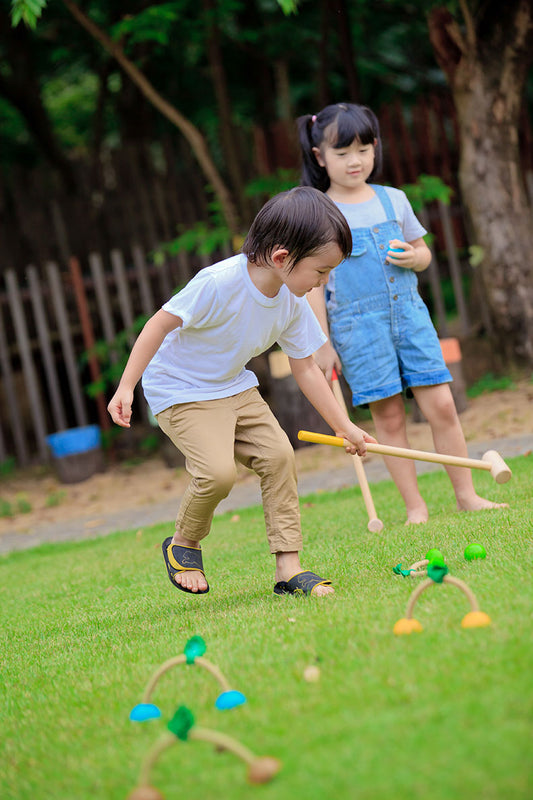children playing outside with  a Croquet Set by Plan Toys