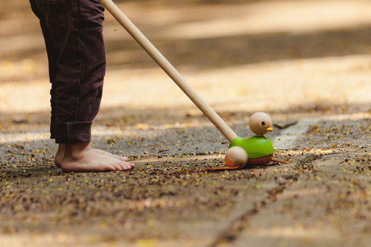 child playing with the Green Duck Push Toy by Plan Toys