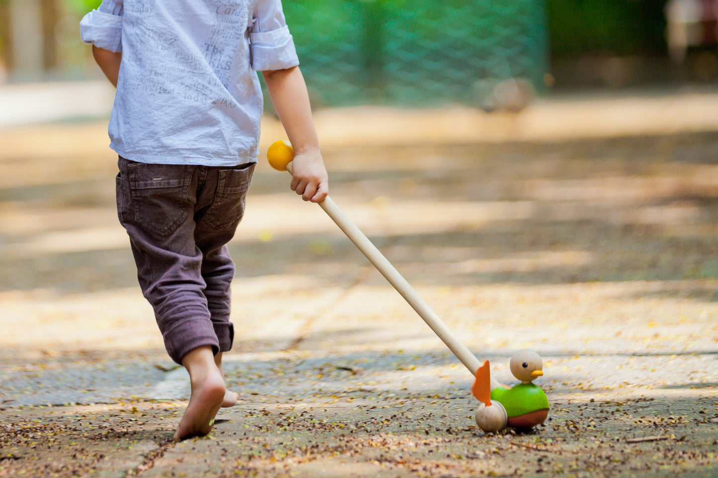 child playing with the Green Duck Push Toy by Plan Toys
