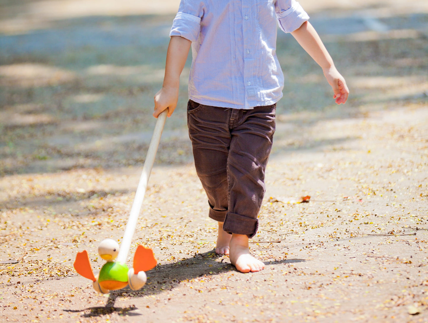 child playing with the Green Duck Push Toy by Plan Toys