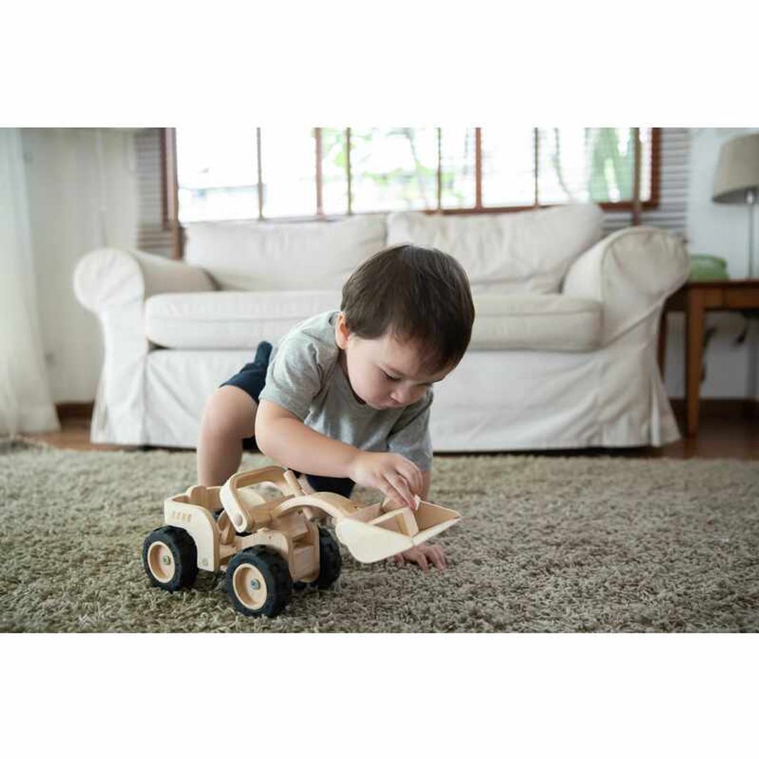 Child in a living room playing with a Bulldozer by Plan Toys