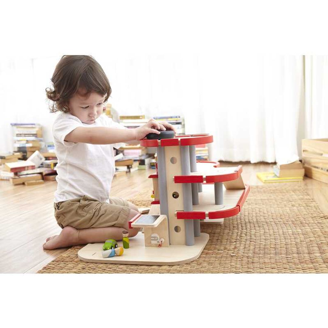 Child Playing with Parking Garage by Plan Toys