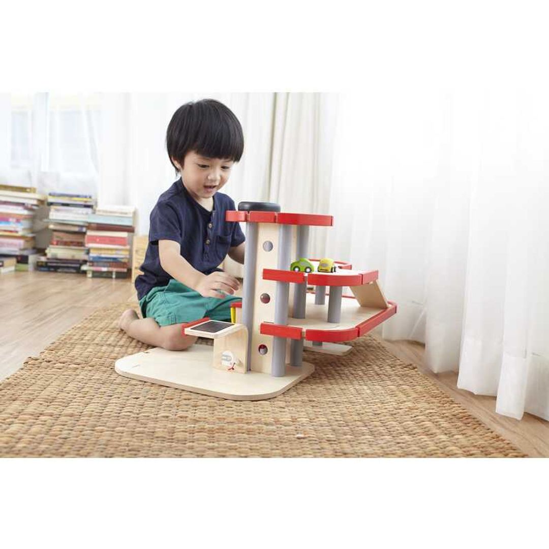 Child Playing with Parking Garage by Plan Toys