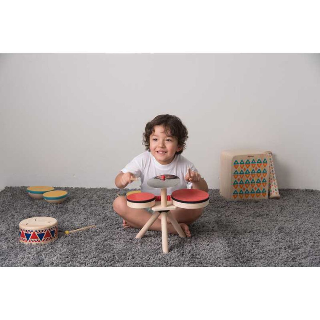 kid playing with Musical Band Drum Kit by Plan Toys
