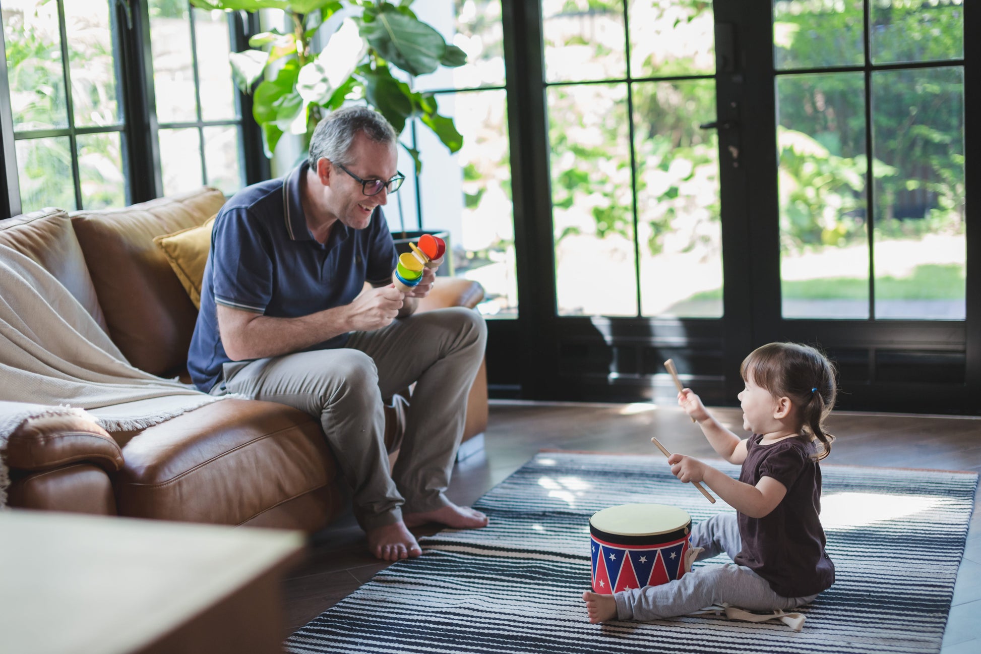 Adult playing with a clatter and Child Playing with Plan toys Big Drum