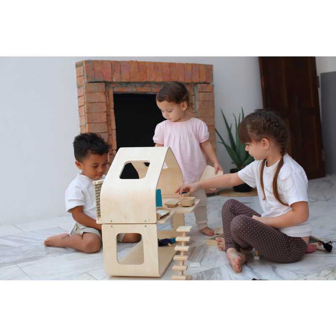 Three kids playing with the Contemporary Dollhouse by Plan Toys