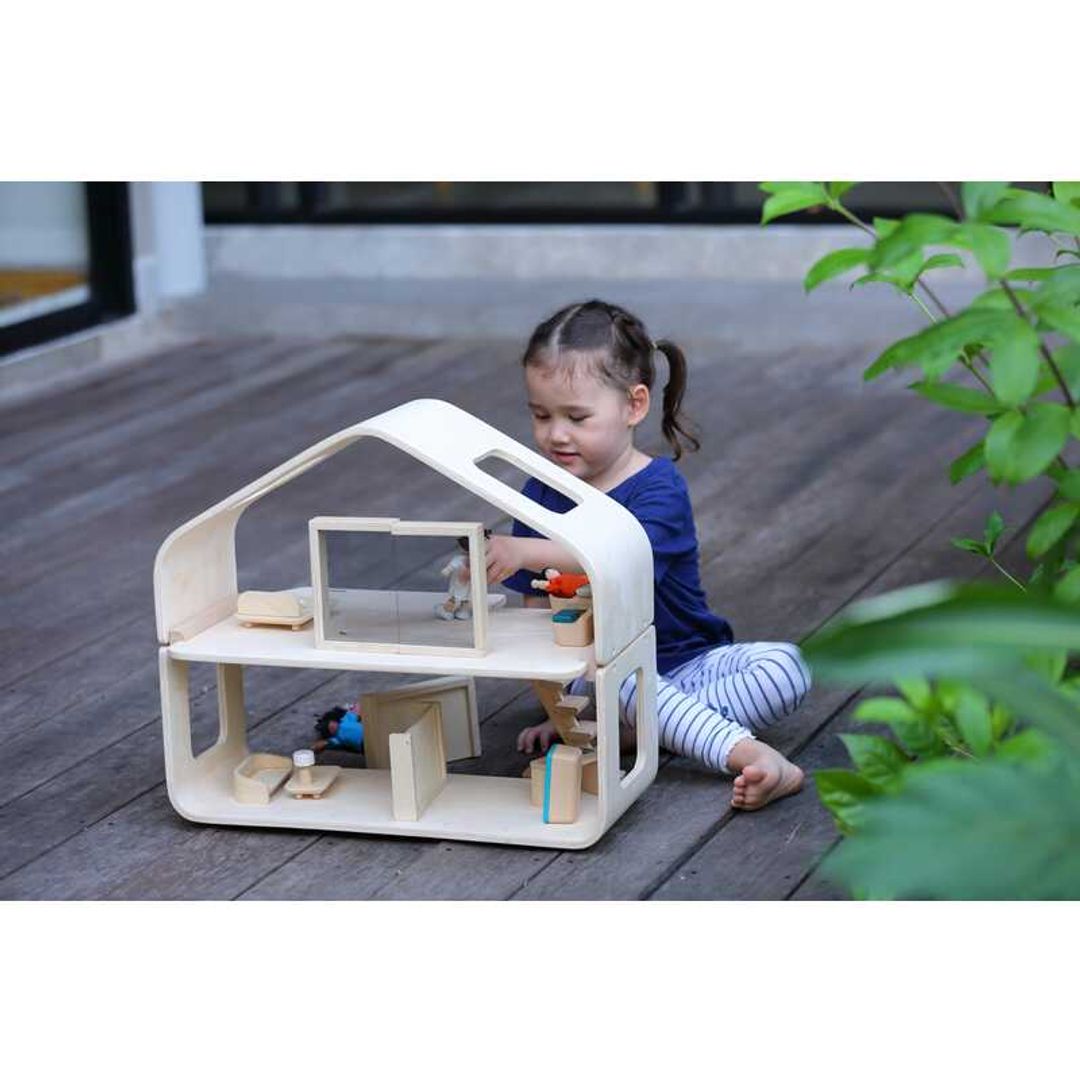 Child Playing with a Contemporary Dollhouse by Plan Toys