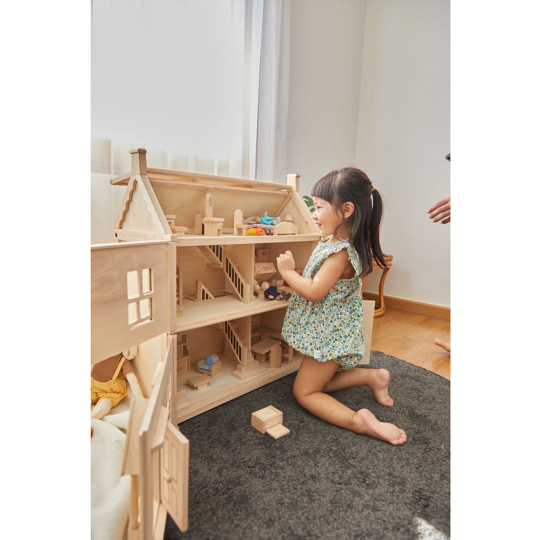 Child playing with a Victorian Dollhouse by Plan Toys