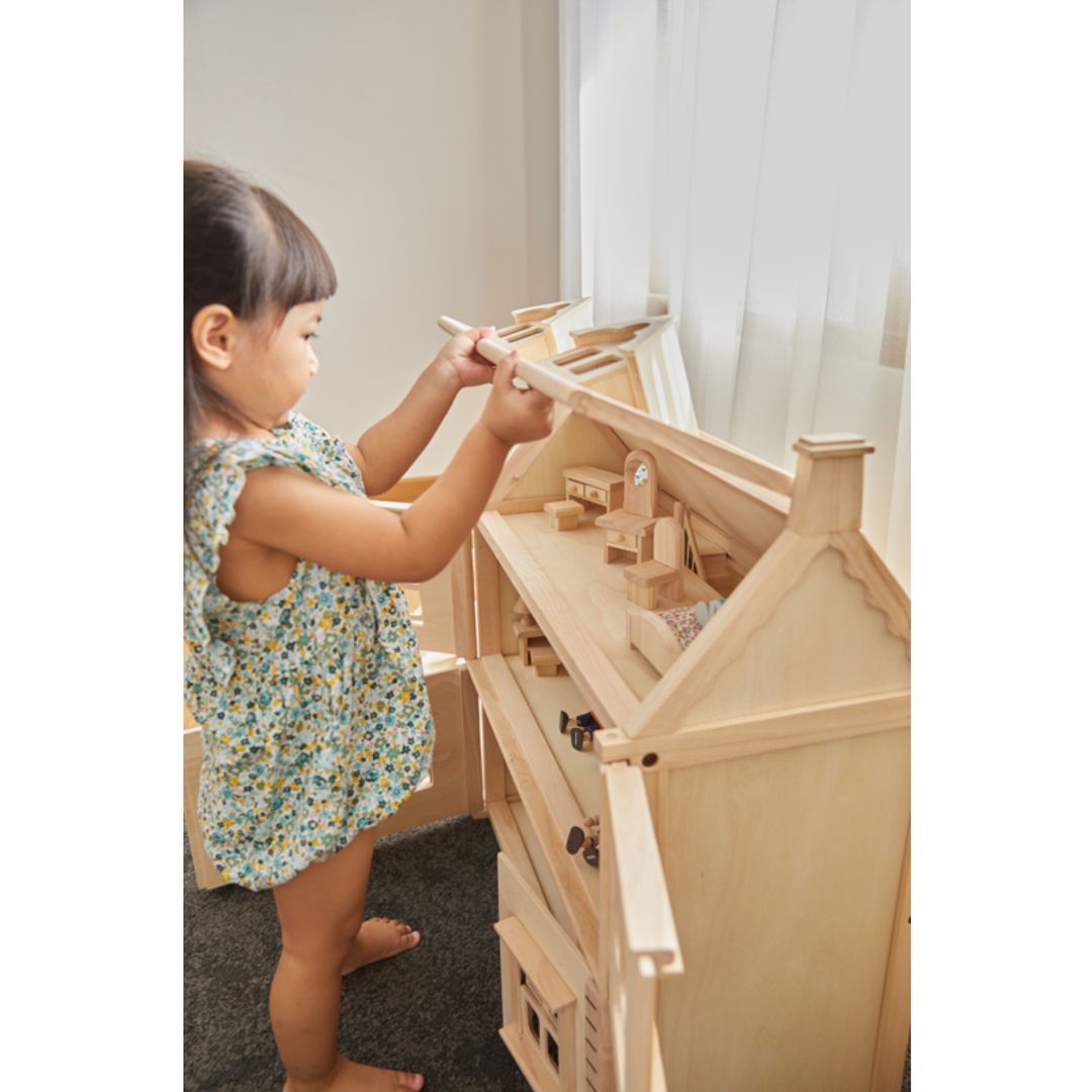 Child playing with a Victorian Dollhouse by Plan Toys