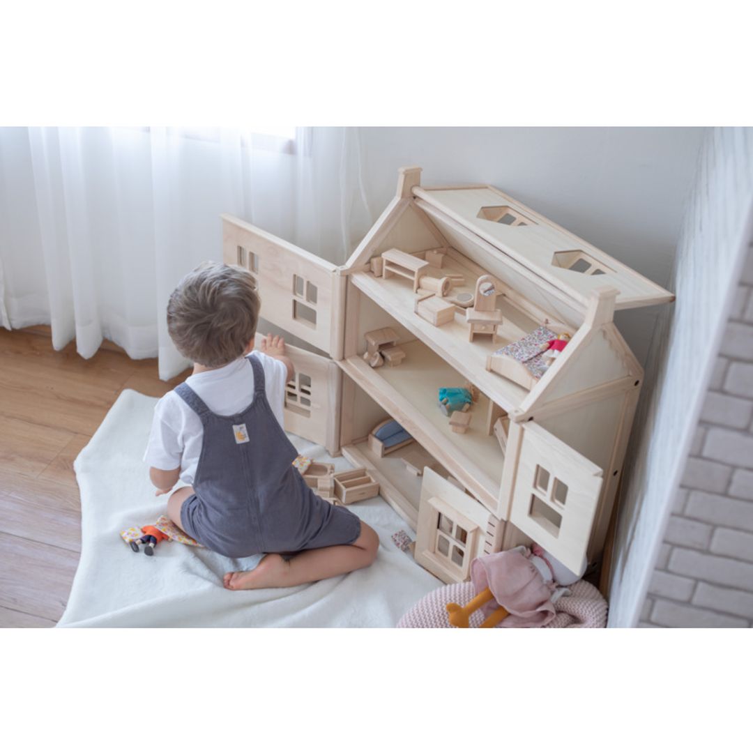 Child playing with a Victorian Dollhouse by Plan Toys