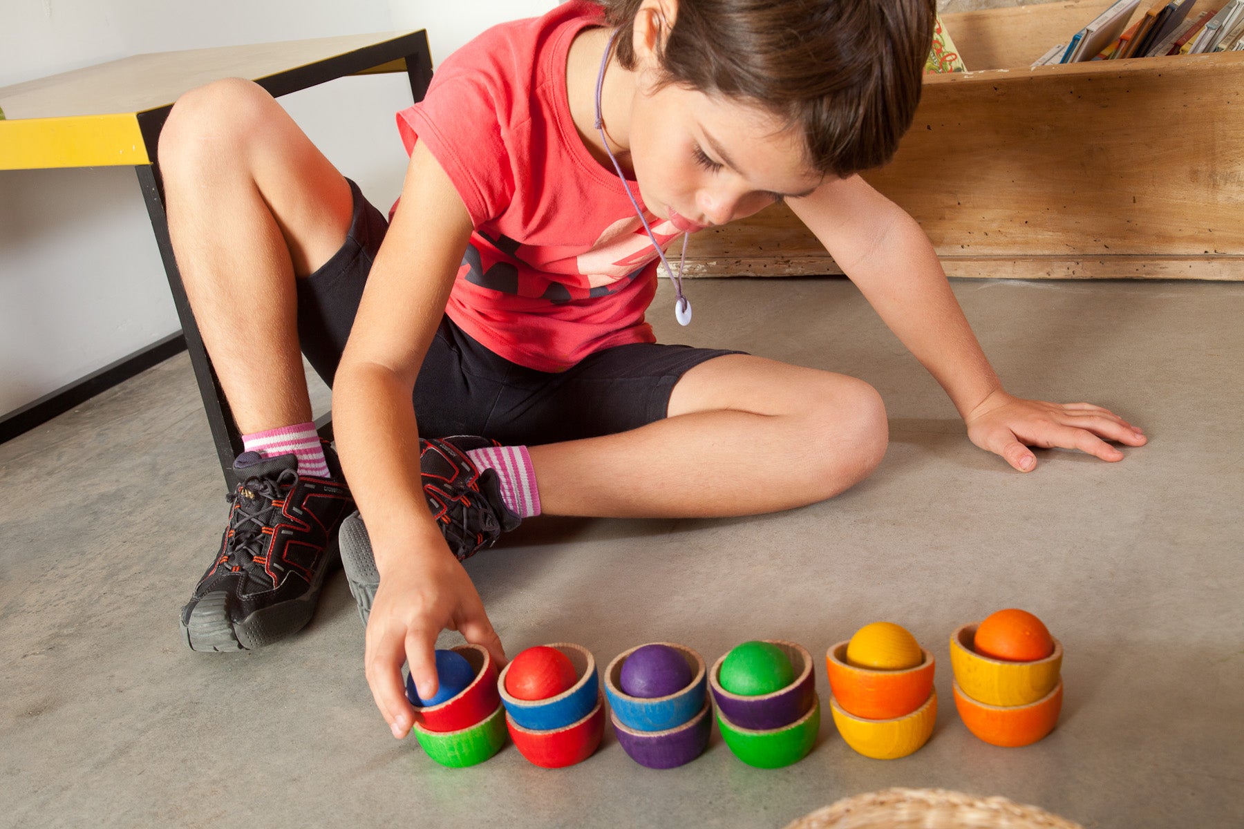 Child playing with rainbow bowls and balls