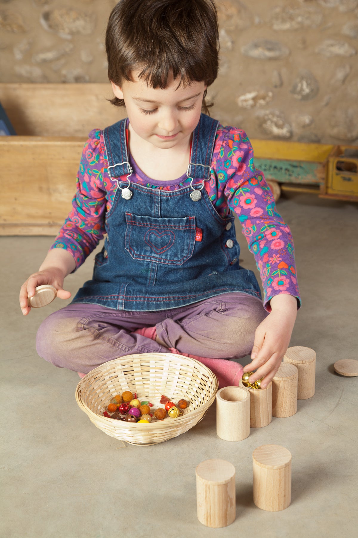 child filling natural cups with beans and beads