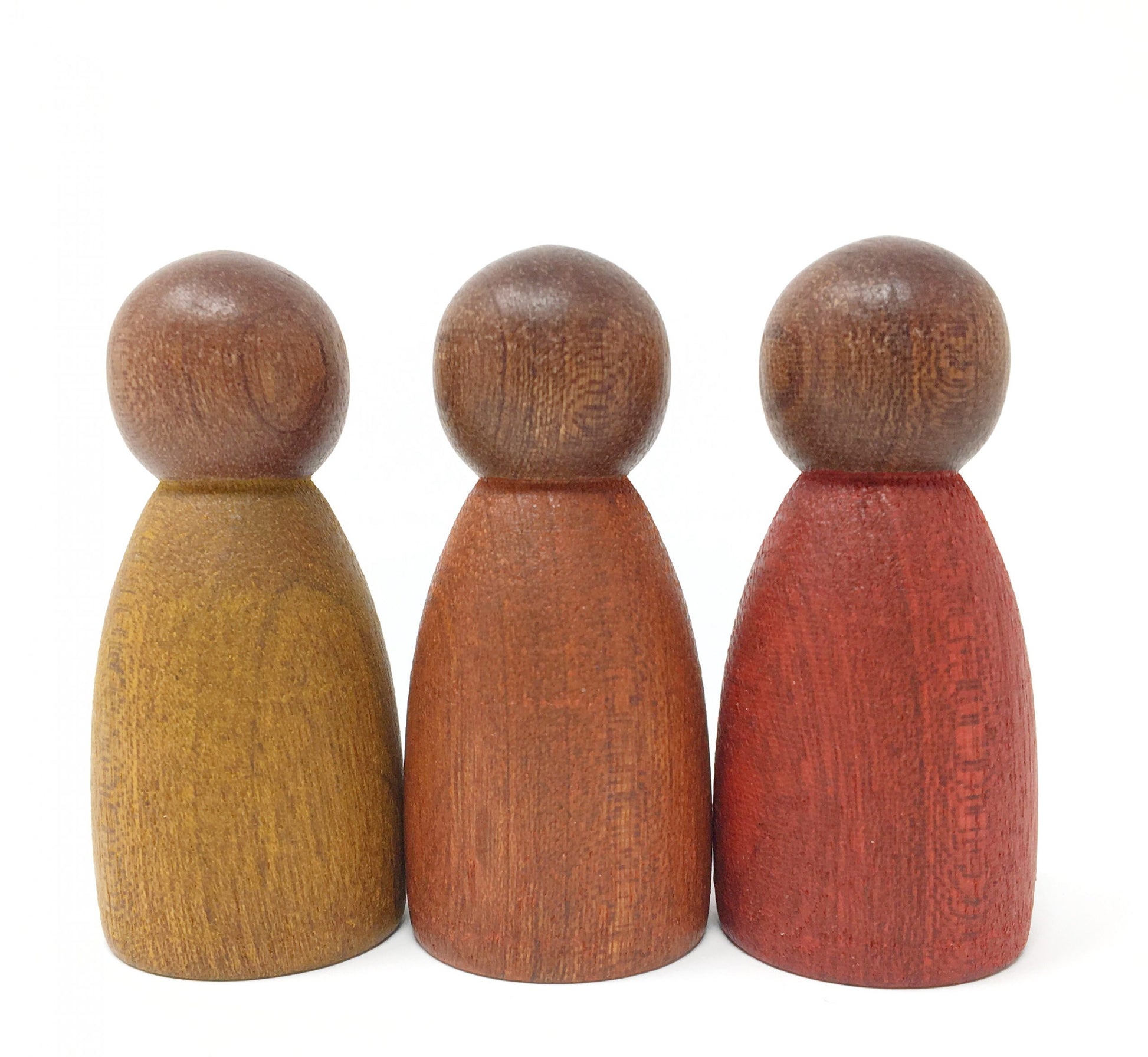 Three wooden peg people, one painted in mustard yellow, one in burnt orange, and one in red, from left to right.