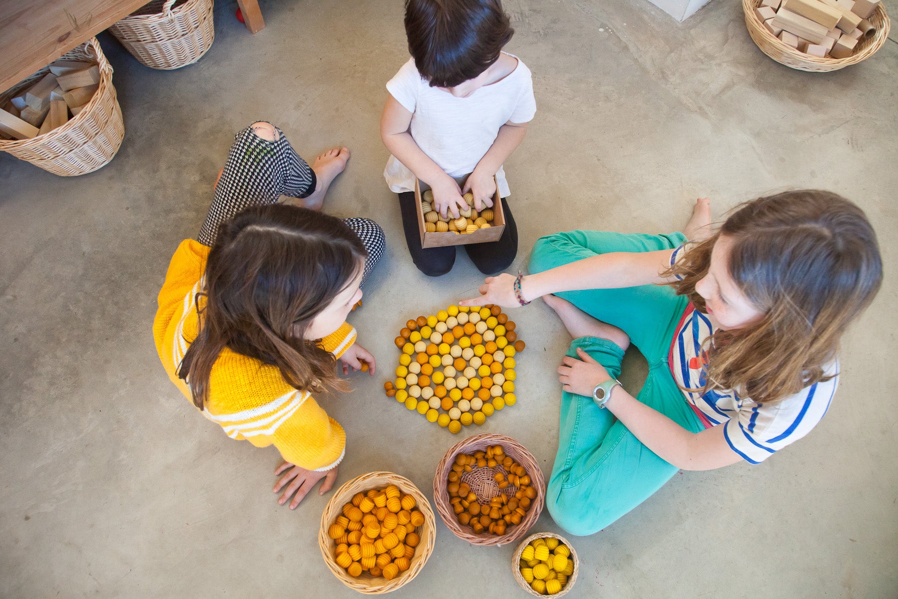 Kids playing with honeycomb and mushroom mandalas in straw baskets