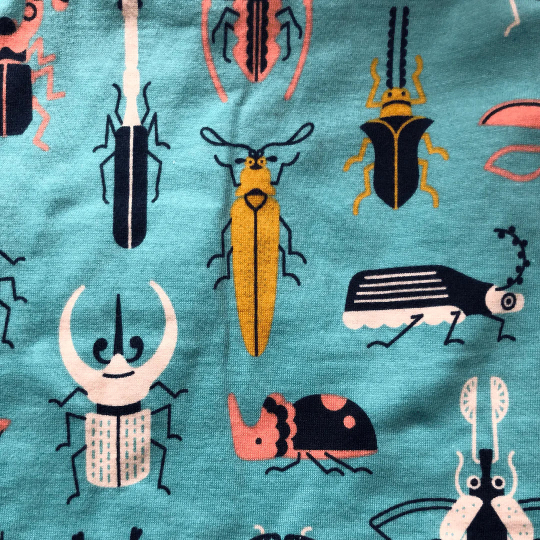 A close-up of a teal fabric with a colorful beetle print.