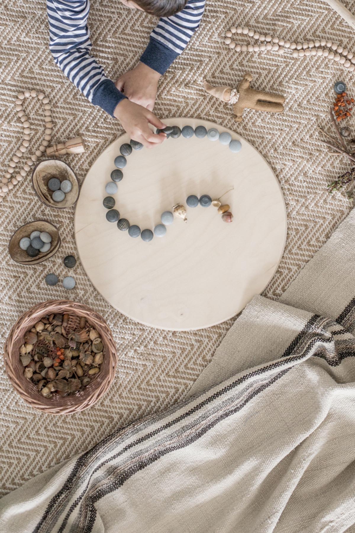 Child playing with stone mandala on wooden platform