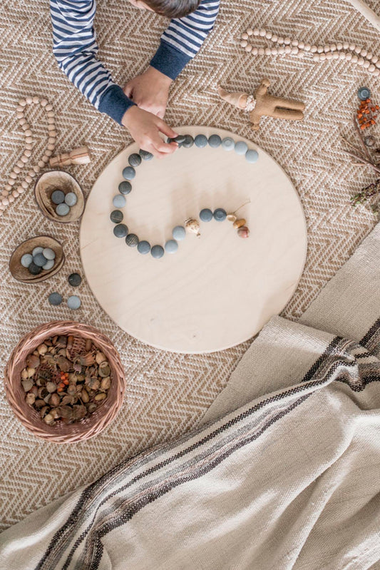 Child playing with stone mandala on wooden platform