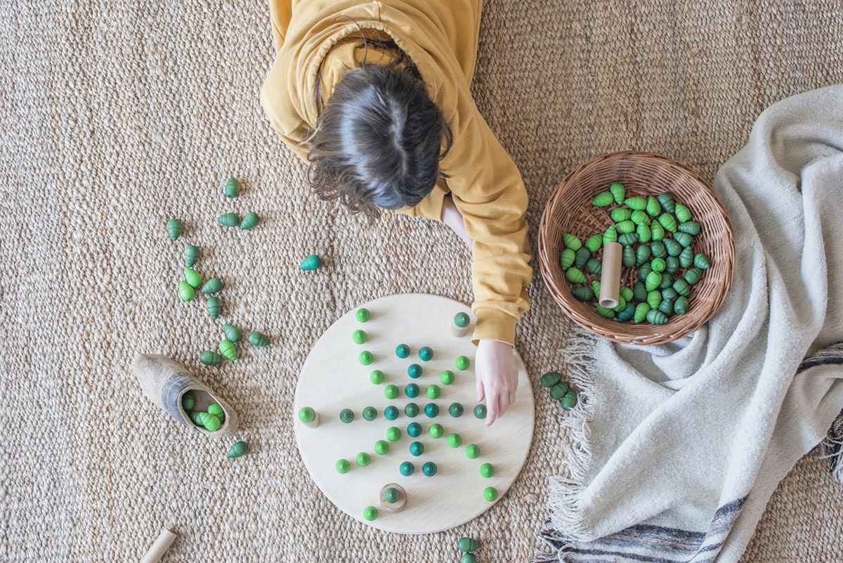 Child laying out tree mandala pieces on a round wooden platform