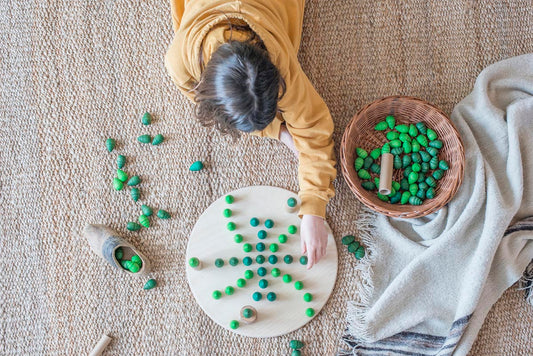 Child laying out tree mandala pieces on a round wooden platform