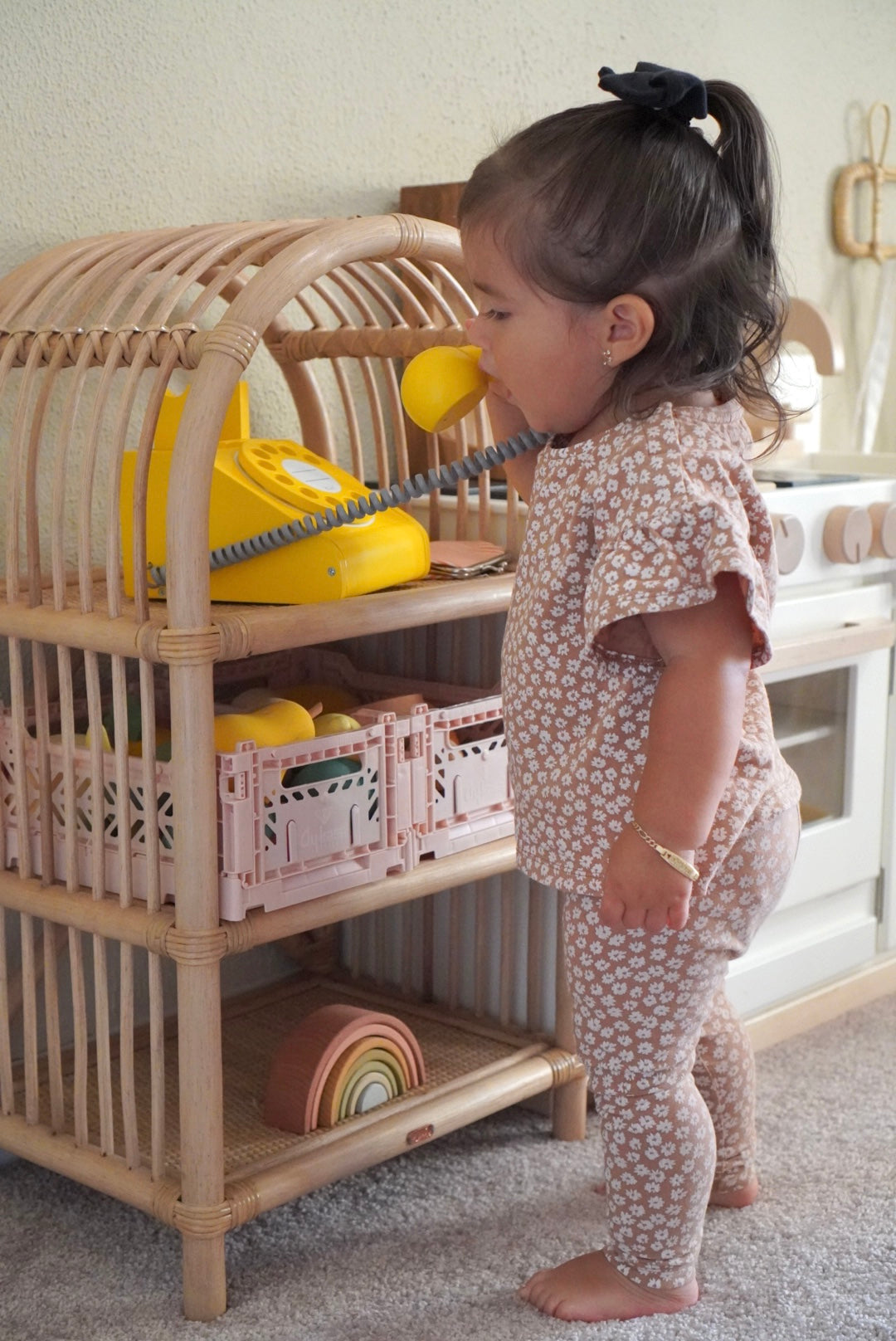 Child talking on a phone in from of the play shelves