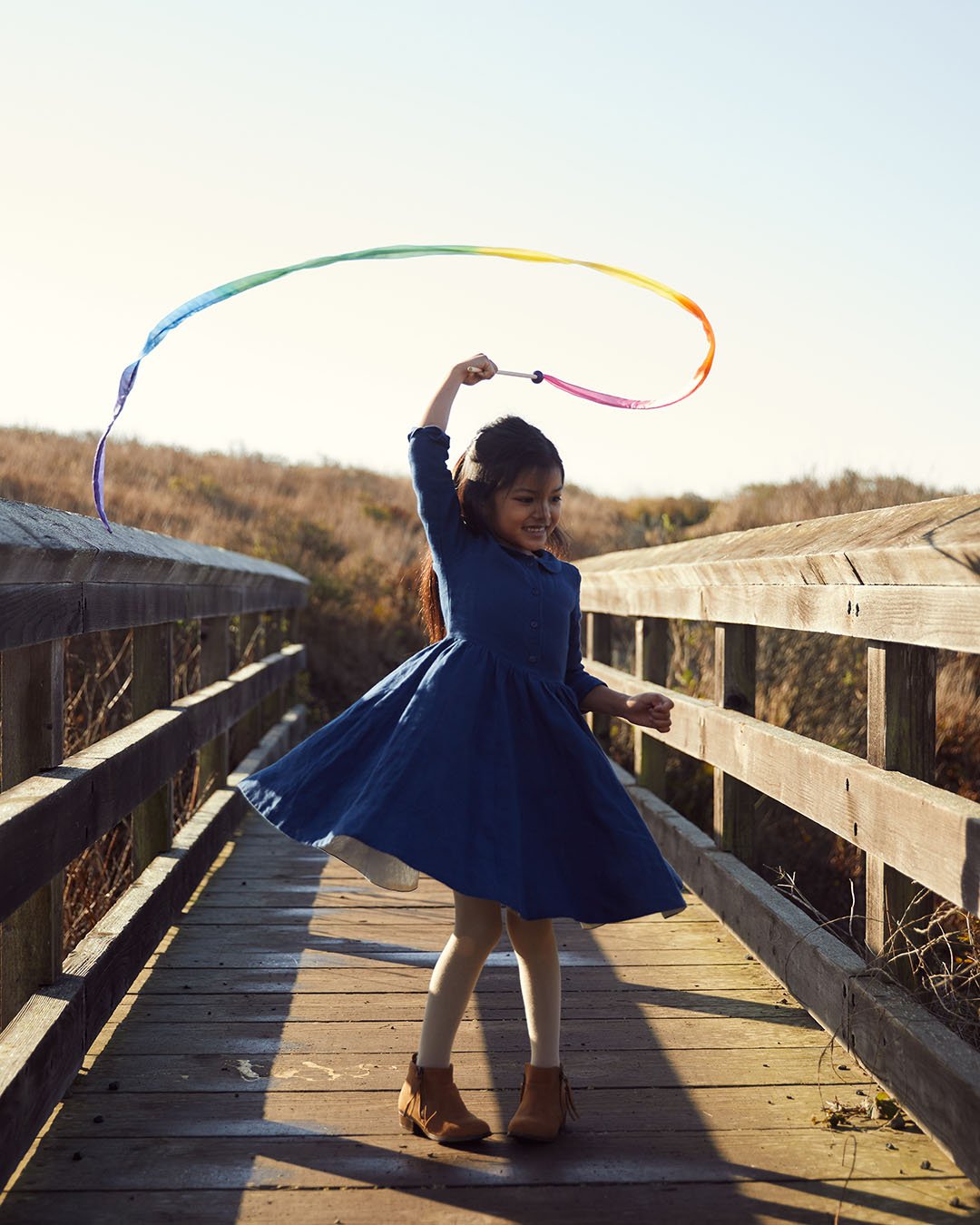 Child playing with Large Rainbow Streamer on a wooden bridge