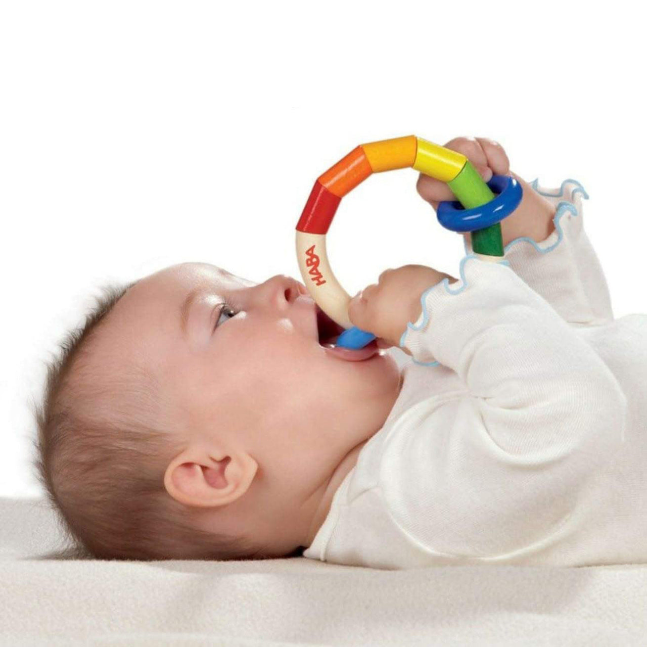 Baby chewing on Kringelring Teething Rattle by Haba