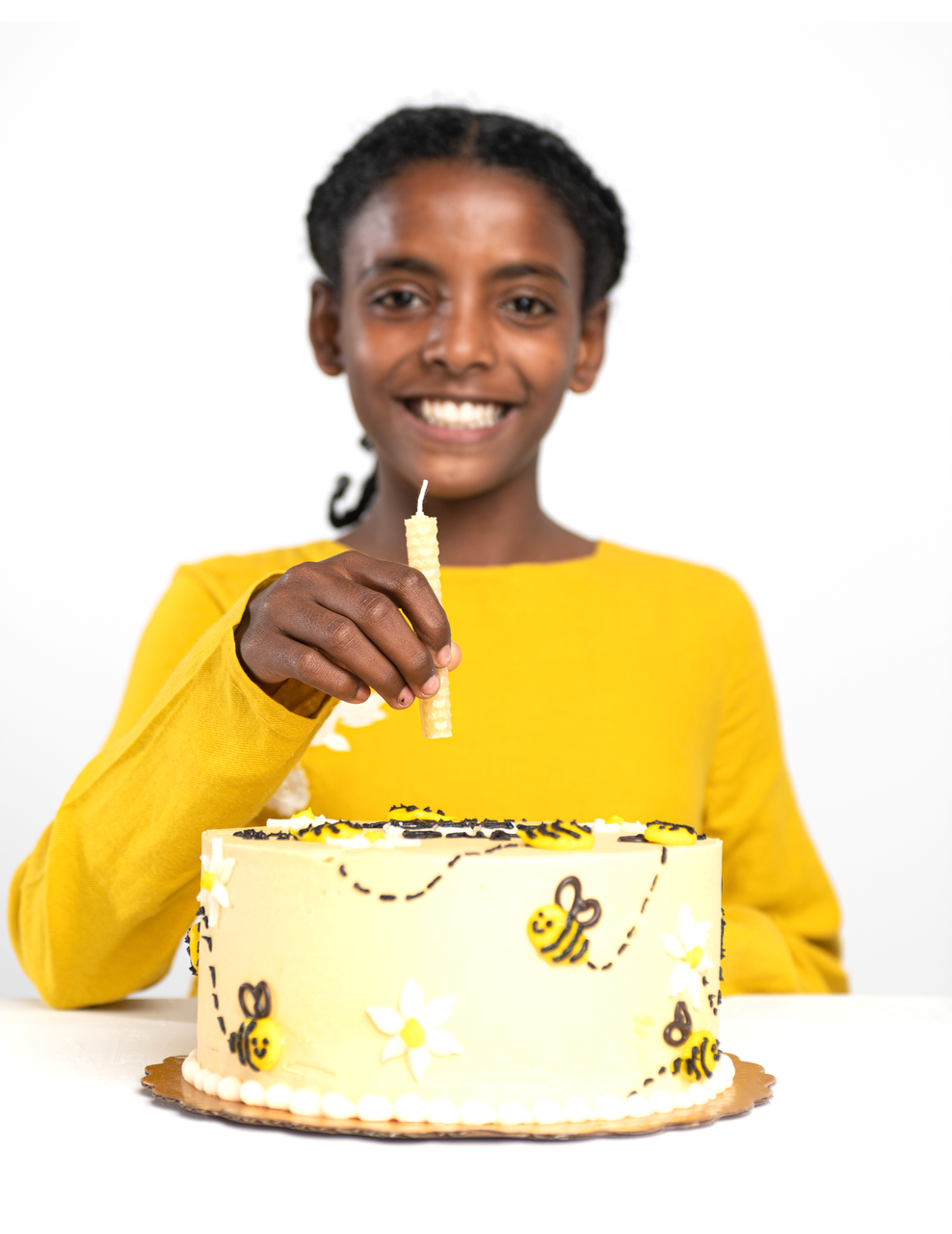 Kid holding a beeswax candle over a cake