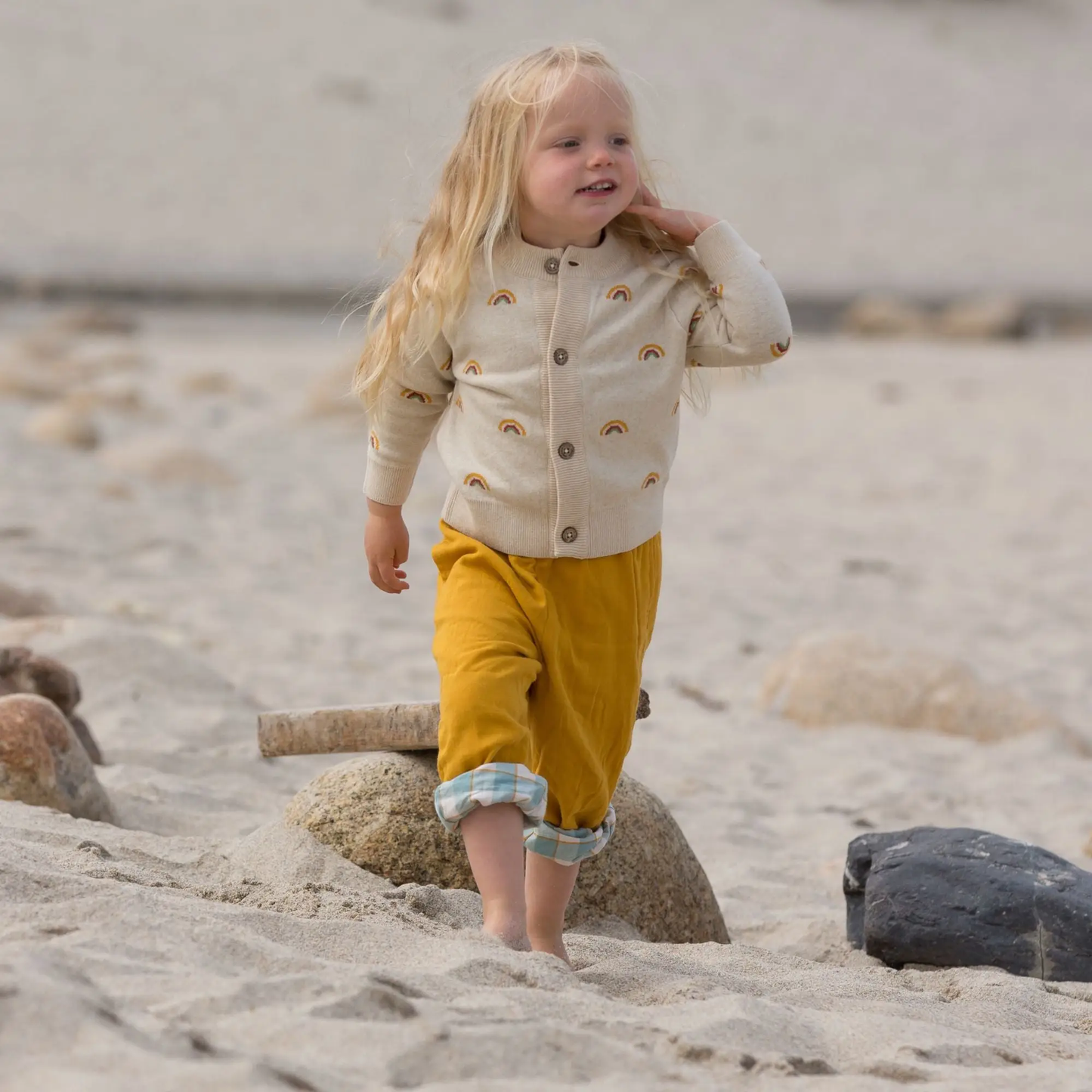 Child on a beach with blonde hair From One To Another Rainbows Knitted Cardigan Sweater