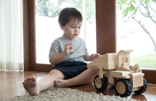Child Playing with the Plan Toys Dump Truck