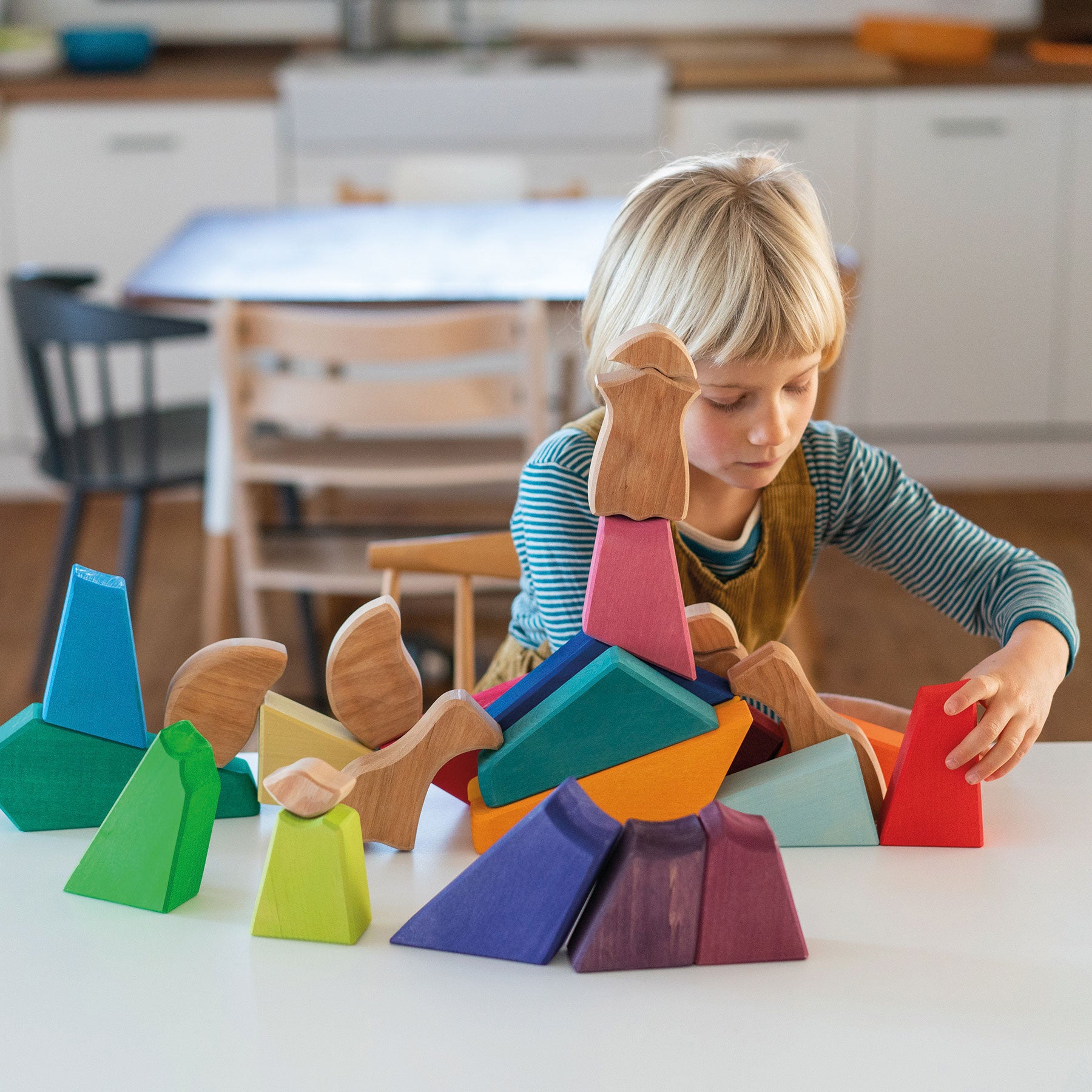 a child playing with rainbow lion ouzzle on a kitchen table