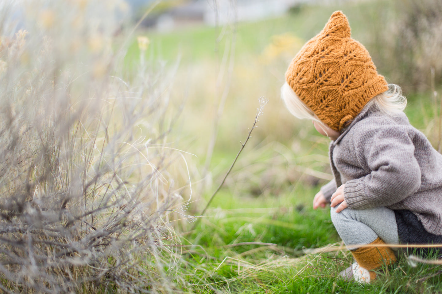 Kid outside wearing a merino wool bonnet 
 and sweater by Nooks Design