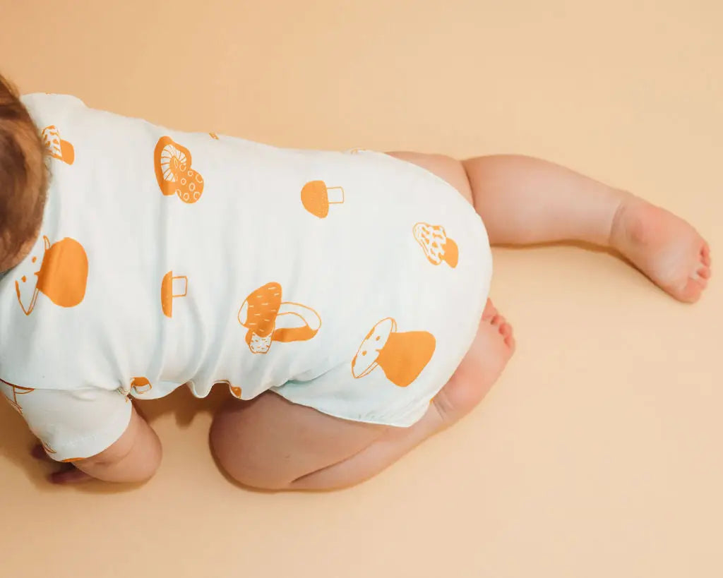 Baby crawling wearing mushroom bodysuit