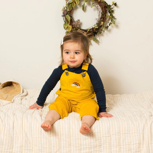 Child wearing embroidered rainbow corduroy dungarees