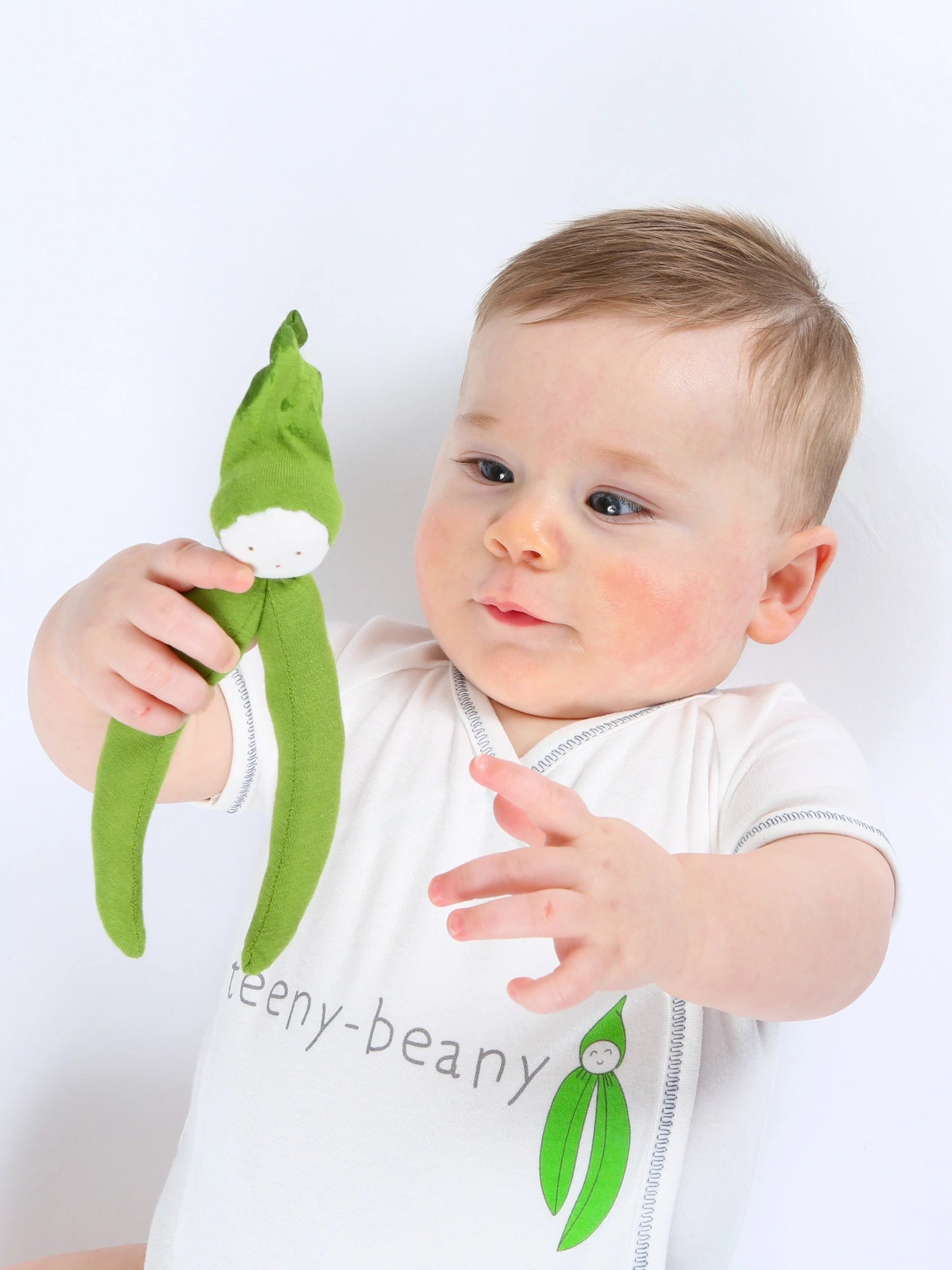 Baby holding an Organic green beans toy