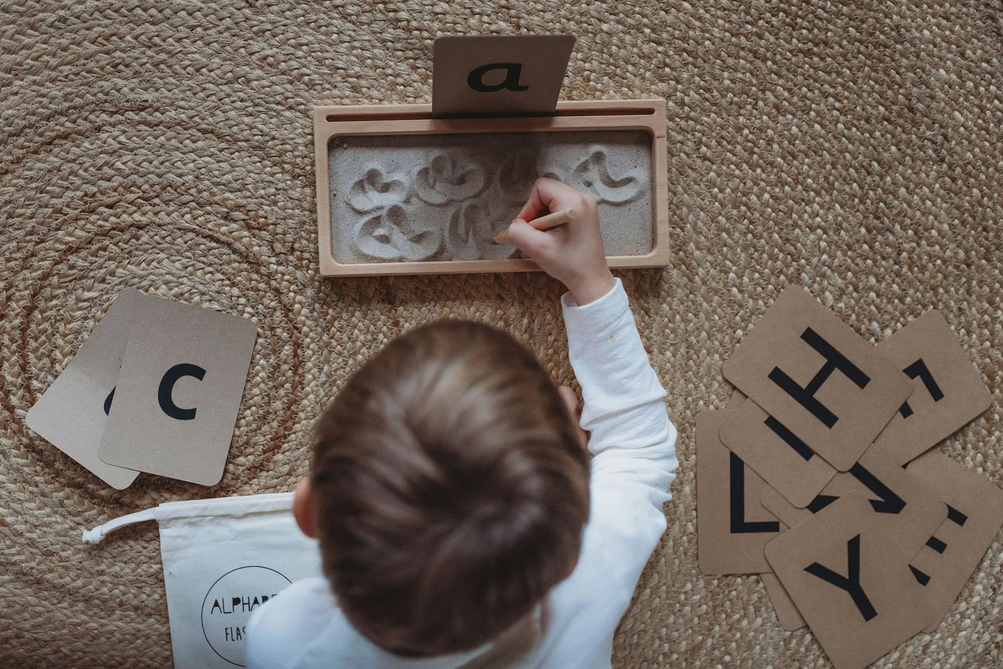 Kid practicing the letter "a" on a Sand Writing Tray 