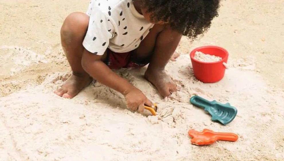 child on the beach playing with sand play set