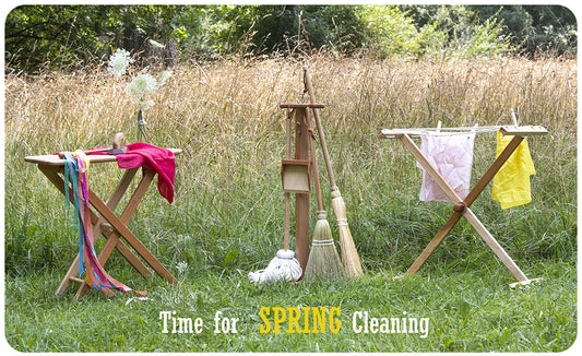 Two wooden drying stands and a broom rack in a tall grass field